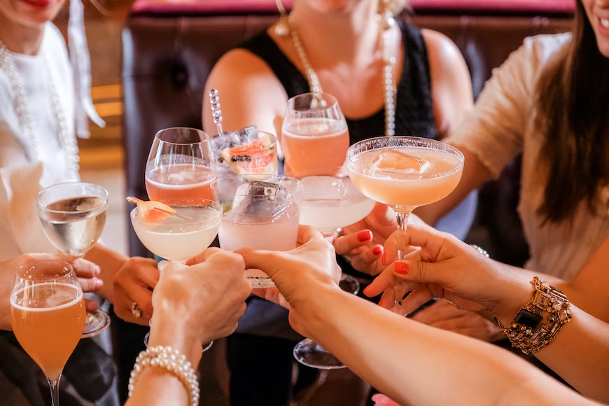 Joyful women raising their glasses for a toast with cocktails.
