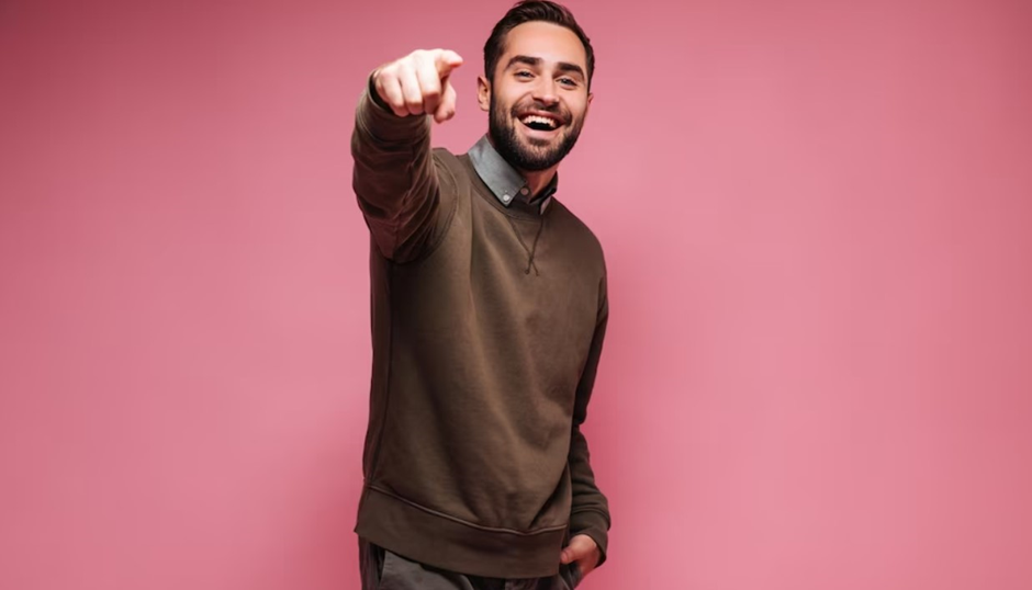 A man wearing a brown sweater with a dress shirt.